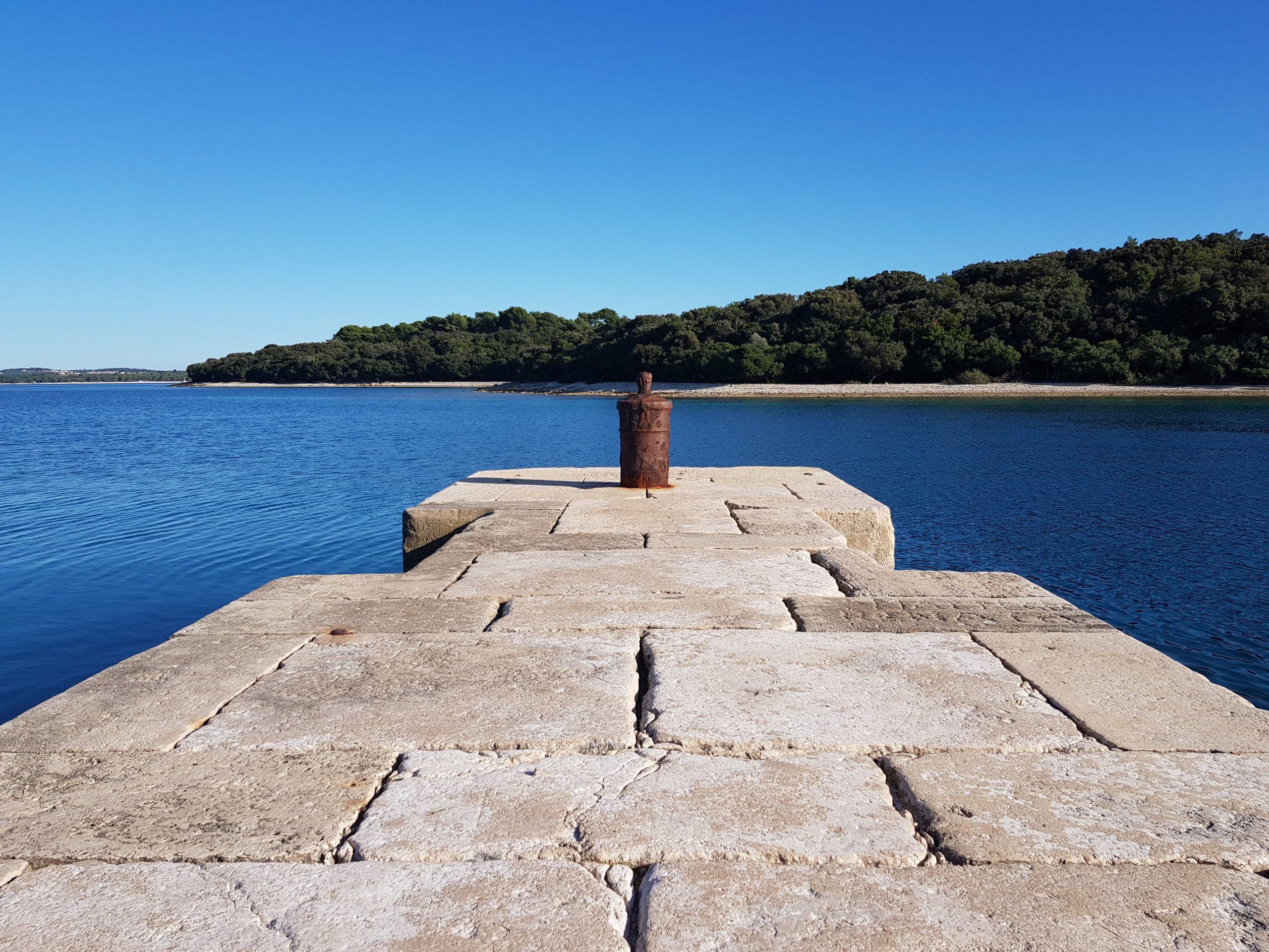 Photo by Ivan Dražić: https://www.pexels.com/photo/stone-pier-on-a-blue-lake-and-trees-on-horizon-13370450/